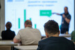 © Anton Gvozdikov - Group of people attending a business presentation featuring a speaker and detailed charts.