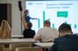 © Anton Gvozdikov - Group of people attentively watching presentation in office setting featuring charts and graphs
