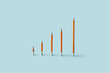 © Yaroslav Danylchenko/Stocksy - Orange pencils arranged as ascending bar graph on blue