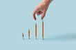 © Yaroslav Danylchenko/Stocksy - Hand reaching toward pencil bar graph on blue background