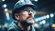 © NovaVision - A construction worker wearing a hard hat and safety glasses looks up in a factory.