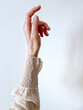 © Ari - Close-up of a raised female hand wearing a vintage handmade blouse with delicate crochet cuff and ruffled sleeve detail