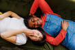 © BONNINSTUDIO/Stocksy - Two happy friends laughing and lying on a green sofa