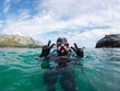 © Alvaro Lavin/Stocksy - Scuba diver gesturing peace sign in the ocean near the coast