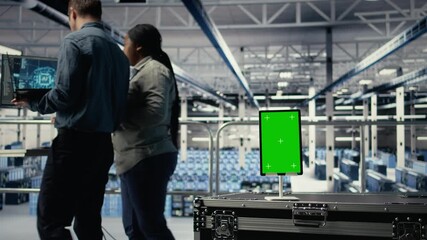 Green screen tablet in server room in front of admins optimizing deep learning systems handling tasks. Mockup device used by data center workers adjusting AI model parameters, camera A