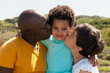 © Anna Fedorova/Stocksy - Father and Mother kissing Their Child Close Up