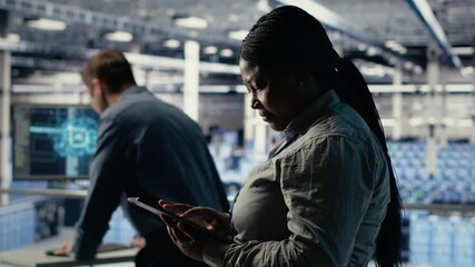 Software developers monitor server hub activity using tablet. Data center employees doing brainstorming, reviewing equipment tests results on devices to ensure systems are working correctly, camera B