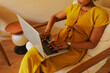© BONNINSTUDIO/Stocksy - Woman working on laptop sitting on armchair at warm office