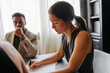 © BONNINSTUDIO/Stocksy - Lawyer writing and listening to client in office