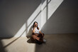 © Javier Díez/Stocksy - Smiling woman sitting on the floor in a sunlit room