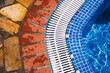 © Natalia Mishina/Stocksy - Poolside view showcasing vibrant tiles and textured stone path