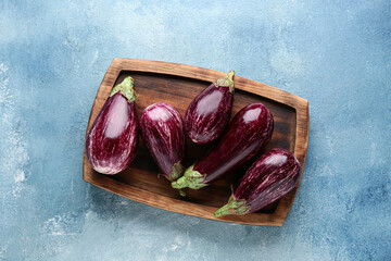Wall Mural - wooden board with fresh ripe eggplants on light blue background