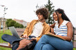 © Alvaro Lavin/Stocksy - Students collaborating on a project using laptop in a park