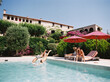 © BONNINSTUDIO/Stocksy - Friends diving into swimming pool at luxury hotel resort