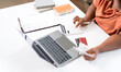 © NAMPIX - Close-up of woman using calculator, laptop, and credit cards for financial planning.