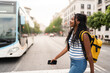 © Alvaro Lavin/Stocksy - Young black woman crossing the street holding a smartphone