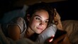 © Bhavesh - Young woman lying in bed at night using smartphone, illuminated by screen light, relaxed and happy expression, late-night browsing and social media scrolling concept in cozy home setting