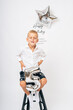 © Elena - Little boy celebrating 5th birthday with silver balloon in studio