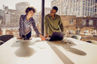 © Westend61 - Businesswomen discussing over laptop standing at desk in office