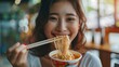 © SUPHAKPHEN - young woman eating noodles relaxed.