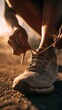 © Jiraphat - A close-up view of a person tying their running shoe, capturing a moment of preparation for exercise during sunset.