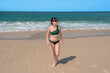 © Jose Rey - Young woman with green bikini walking on the beach enjoying summer vacation