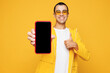 © ViDi Studio - Young middle eastern man wear raincoat casual clothes sunglasses hold use mobile cell phone with blank screen workspace area show thumb up isolated on plain yellow orange background Lifestyle concept.