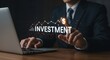 © alvi - A businessman in a suit interacts with a digital investment graphic on a laptop, pointing at a dollar sign.