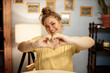 © Anatoliy Karlyuk - Body positive concept. Adorable plus size caucasian woman doing heart shape gesture with hands posing in home interior, expressing self-love and confidence being overweight and beautiful
