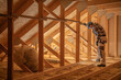 © Tomasz Zajda - Worker Inspecting Insulation in a Residential Attic During Daylight Hours