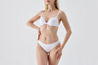© Lustre Art Group  - Blonde woman in white lingerie with hand on waist and confident posture. Concept of lingerie promotion, fashion catalog, feminine elegance, body confidence, modern style.