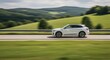 © Razia - White SUV Driving on a Highway Through Green Rolling Hills