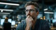 © Jay - Thoughtful man wearing glasses sitting indoors with a pensive expression