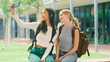 © Monkey Business - Two Female High School Or Secondary Students Posing For Selfie On Phone Sitting On Wall Outdoors