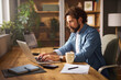 © Stockphotodirectors - A man types on his laptop in a cozy home office. The workspace features wooden furniture, indoor plants, and warm lighting, creating a productive atmosphere for remote work.