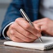 © Fadil - Close-up of a hand writing in a notebook