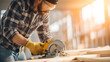 © plaksa - Caucasian construction contractor operating a cordless circular saw, cutting plywood indoors, wearing protective gloves and plaid shirt, safety glasses, dynamic low-angle close-up,