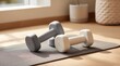 © asAI12 - Two muted-toned dumbbells rest on a gray yoga mat, positioned on a light wood floor near a window, suggesting a home workout space
