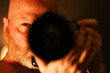 © Mat Hayward - Intense photographer capturing a photo with his camera at night. His bloodshot eye is staring with intensity.