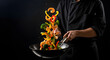 © Chondon - Professional chef tossing vegetables and shrimp in a wok on a black background