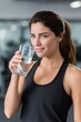 © Bubi Studio - Smiling Latina Woman Drinking Glass of Water After Exercise in Gym