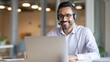 © Jannik - A smiling middle-eastern business man wearing a headset is working on a laptop