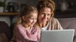 © Popelniushka - Joyful Moments: Young Woman and Mother Sharing Laughter Together While Using Laptop at Home on Cozy Sofa