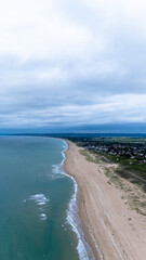 Wall Mural - Expansive beachline meeting ocean under clouded sky.