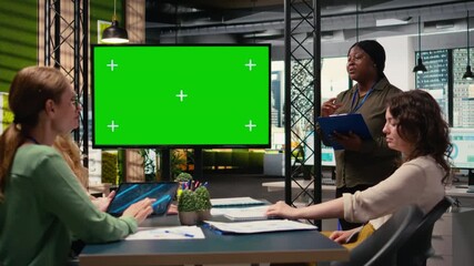 Diverse group of businesswomen collaborates near chroma key monitor in a professional office, using the tv display for financial planning and isolated space for strategy updates. Camera A.