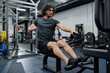 © TrueFrame Collective - Young Caucasian man with curly hair doing strengthening exercise in modern gym using cable row machine
