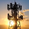 © Hafi - Silhouette of a tall cell tower at sunset, sun shining through the structure