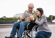 © Westend61 - Smiling people with wheelchair using tablet outdoors in city