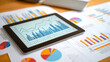 © Rezaul - Digital financial graph on tablet displays business growth analysis. Printed quarterly reports alongside. Comparative analysis clear