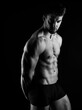 © Anetta - Handsome bodybuilding man posing shirtless on black background flexing muscles and six pack after a workout